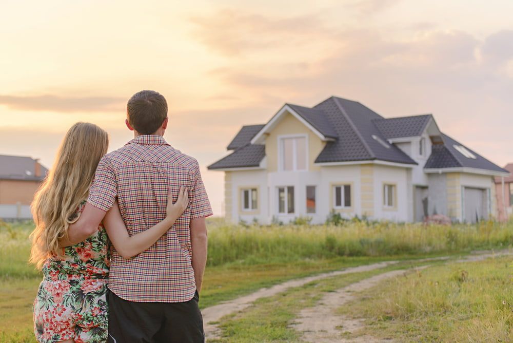 Couple Embraces, Gazing at a Two-story House at Sunset in a Field — Country Coast Valuers in Cundletown, NSW