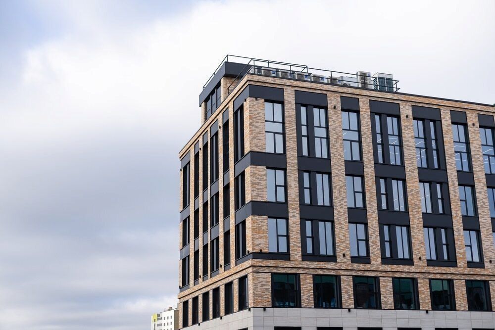 Modern brick building with dark window frames against a cloudy sky - — Country Coast Valuers in Forster, NSW
