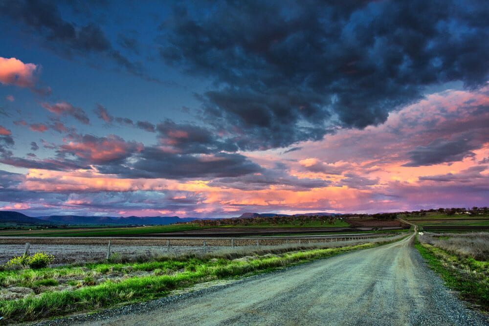 Dirt Road Stretches Into the Distance Under a Colourful Sunset Sky — Country Coast Valuers in Old Bar, NSW