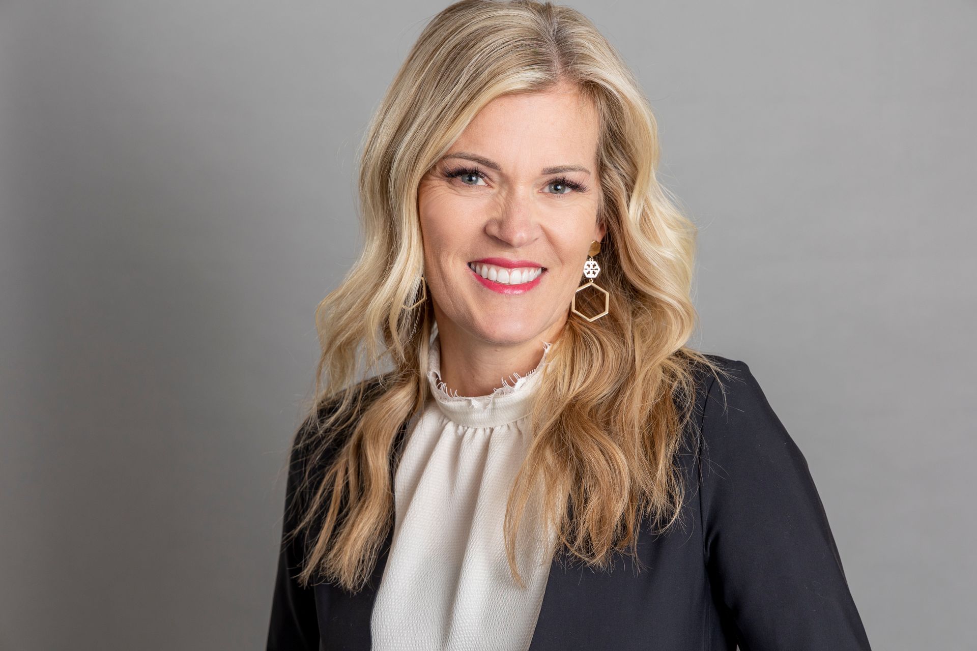 A woman in a black jacket and white shirt is smiling for the camera.