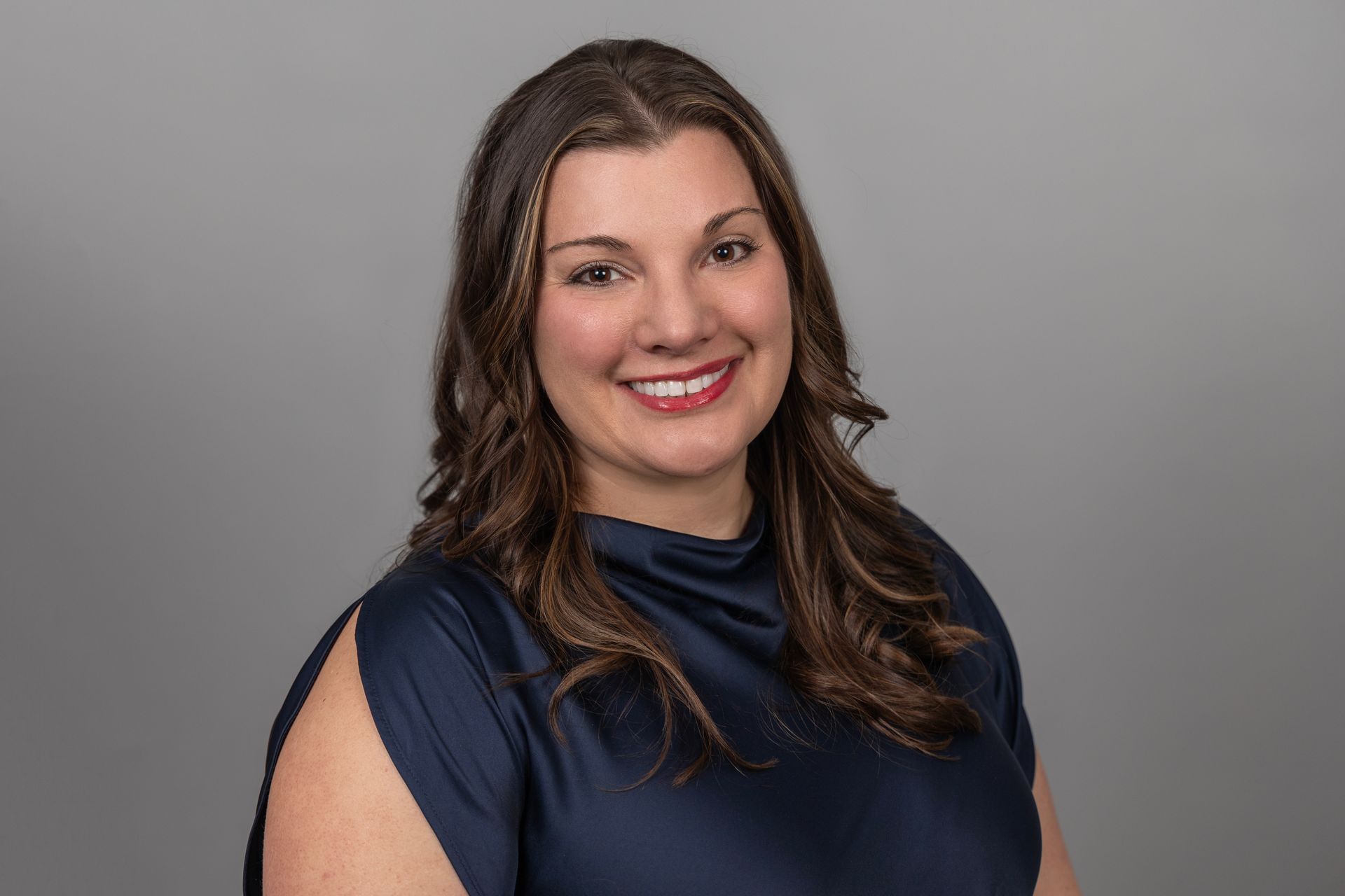 A woman in a blue shirt is smiling for the camera.