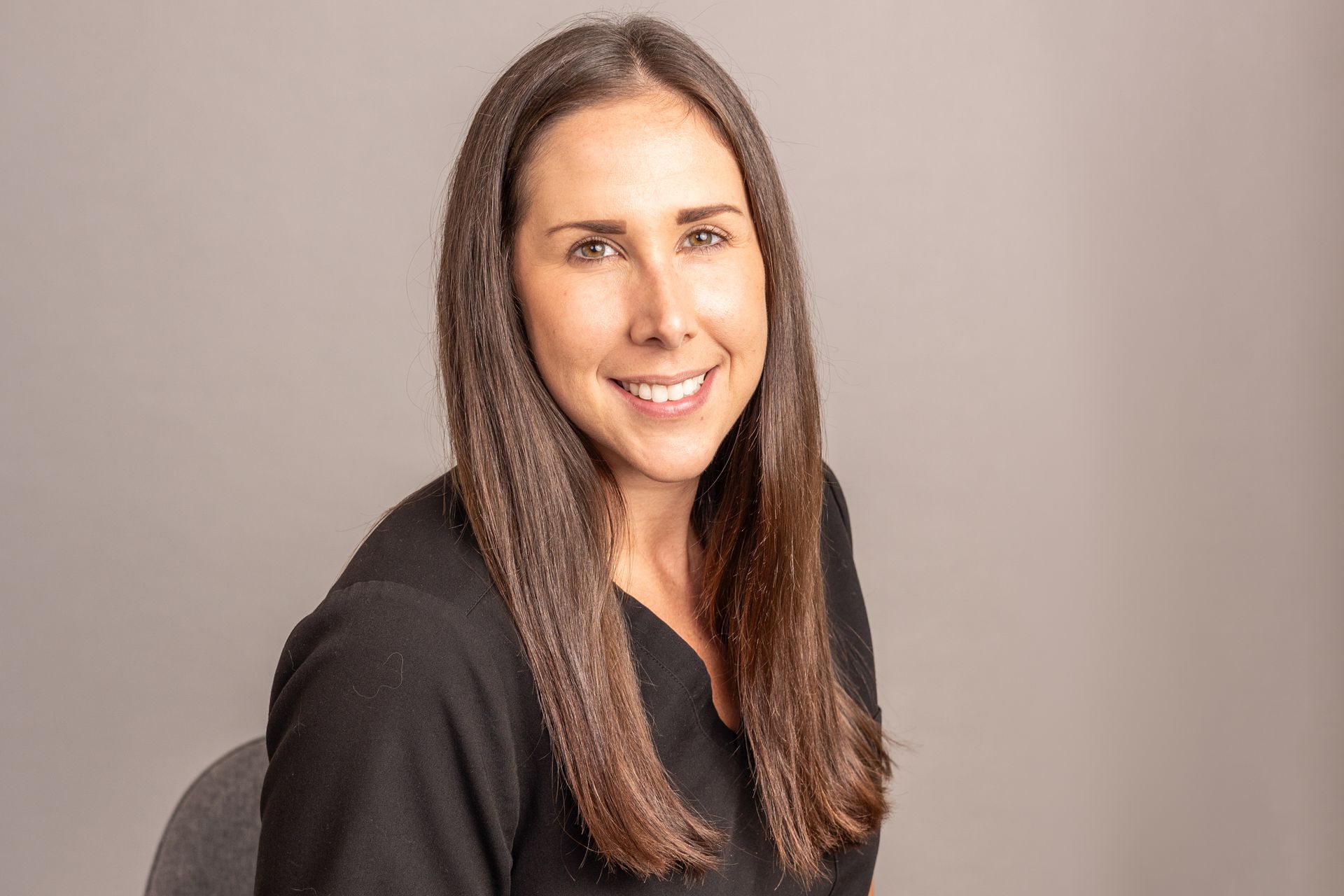A woman is sitting in a chair and smiling for the camera.