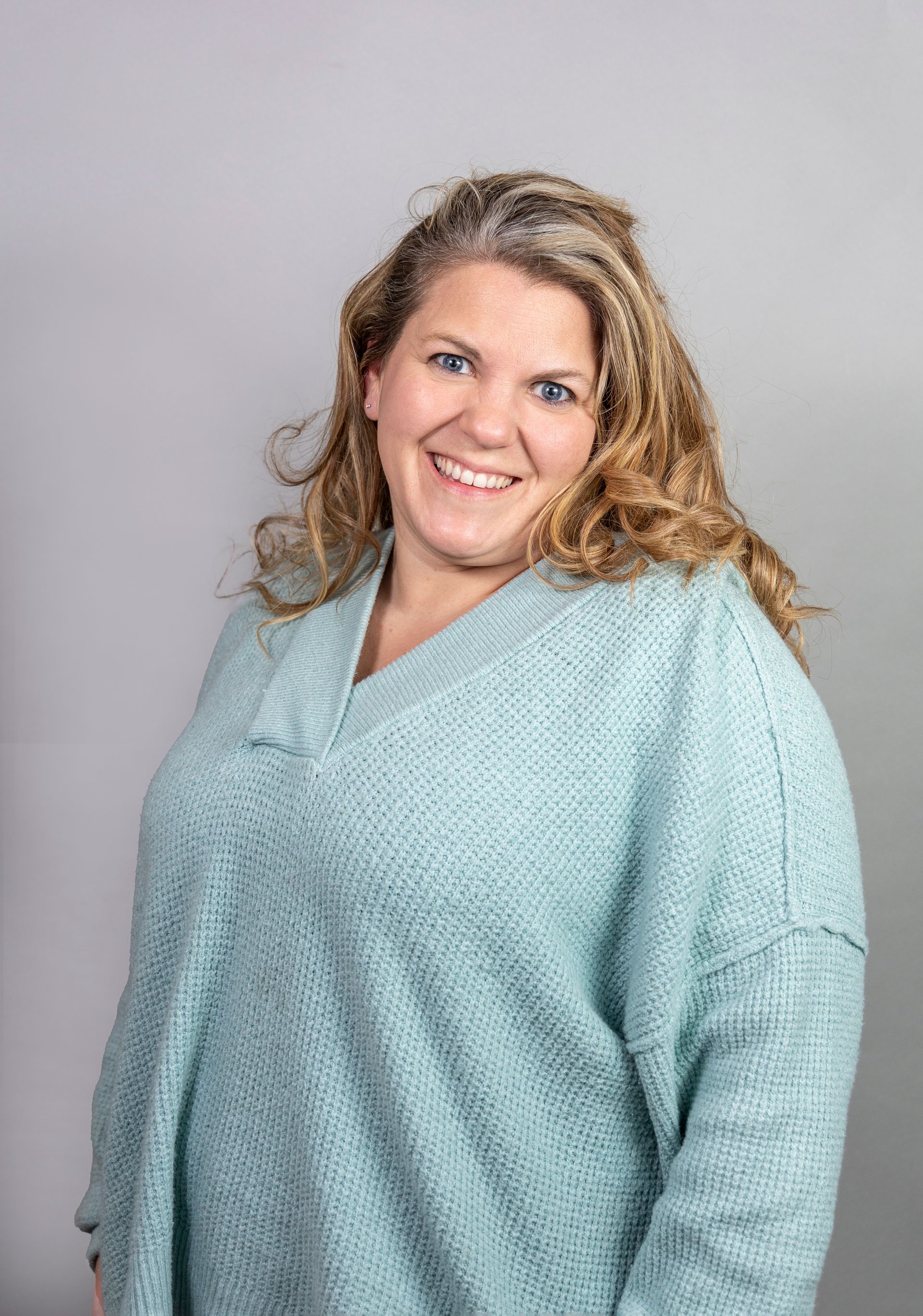 A woman in a blue sweater is smiling for the camera.