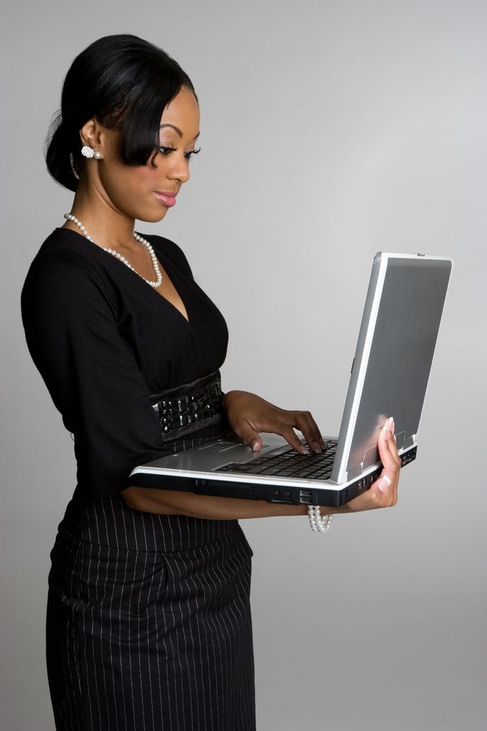 Woman in black dress working on a laptop.