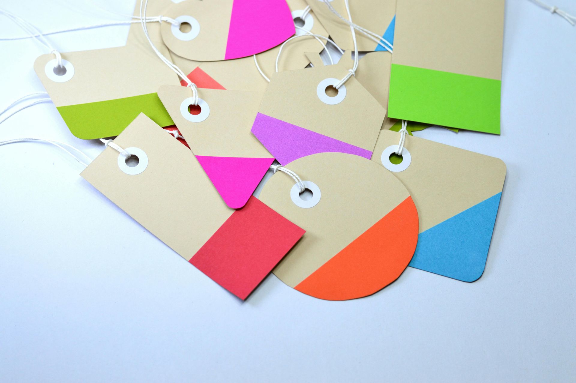 Kraft paper tags with colorful geometric painted designs, white strings.