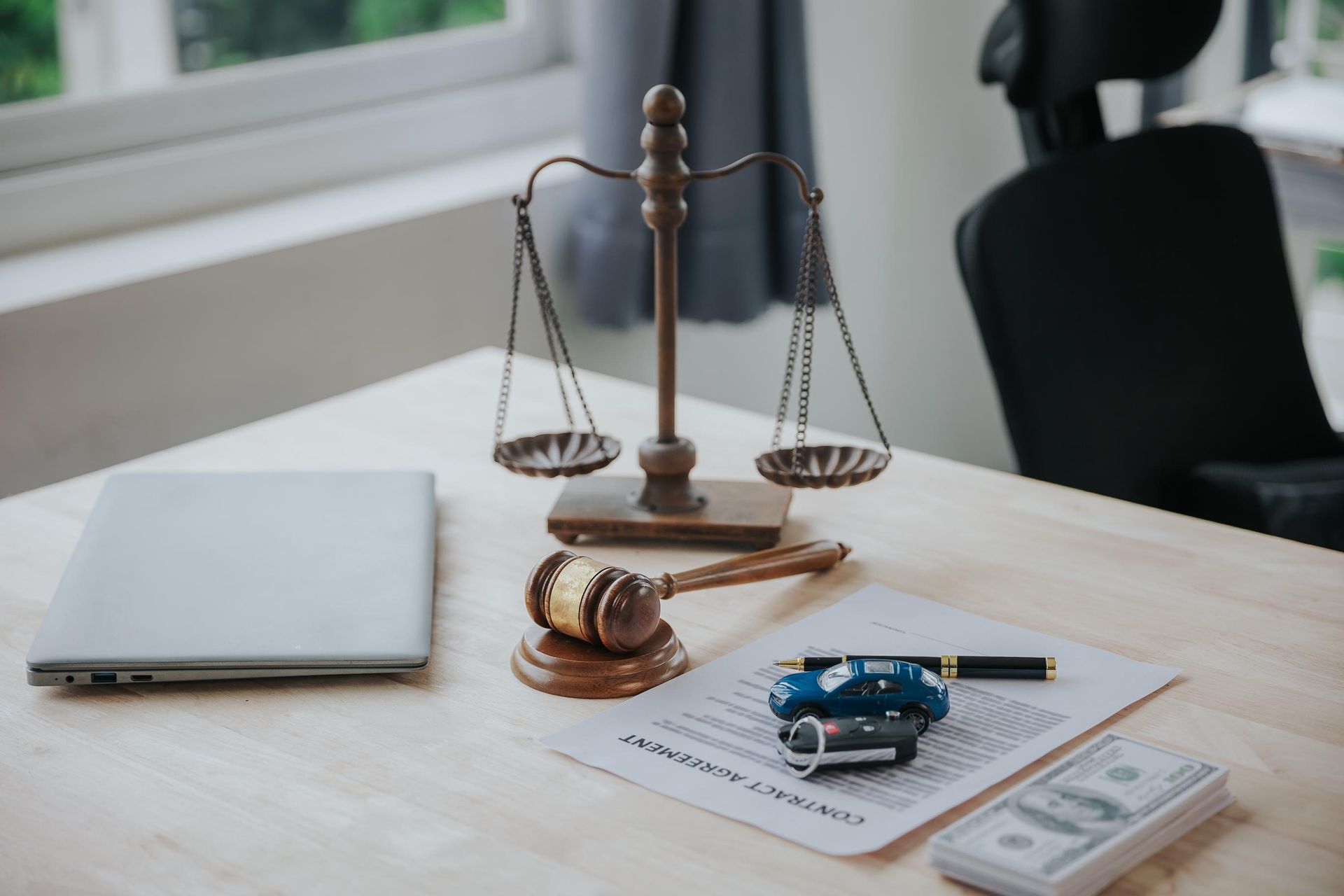 Law office desk with gavel, scales of justice, car keys, and documents