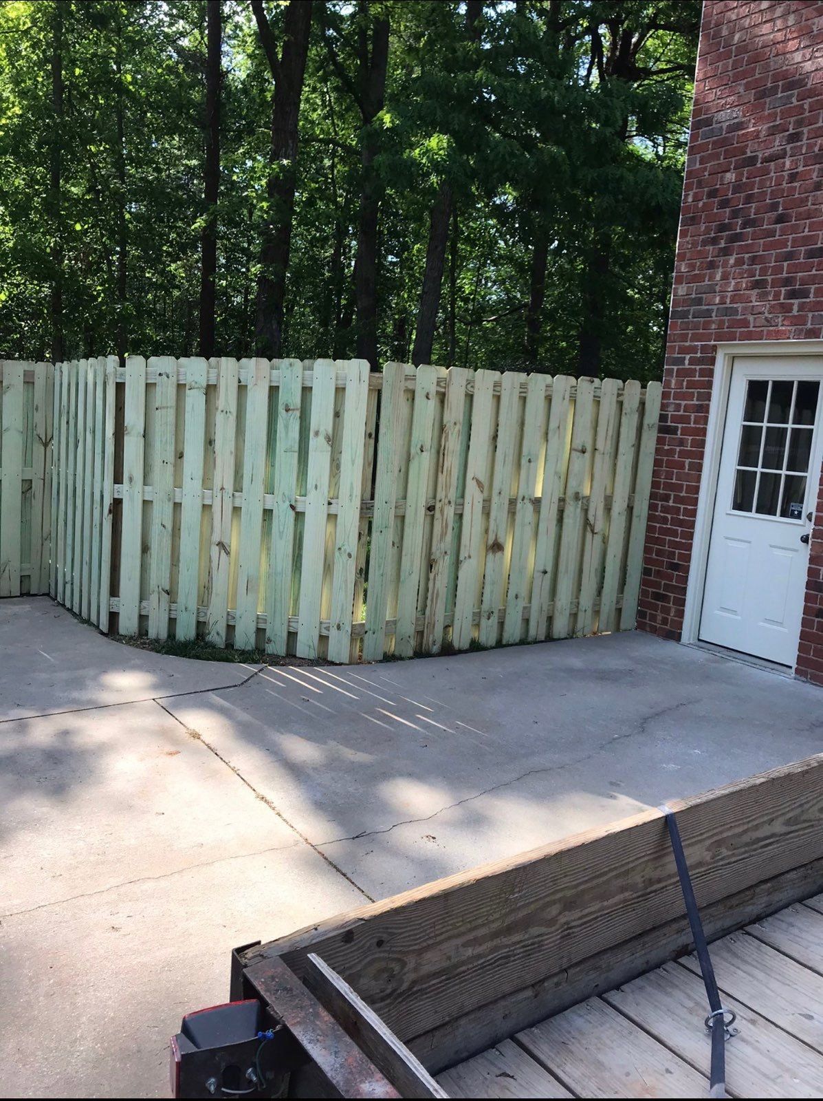 A wooden shadow box fence is in front of a brick building