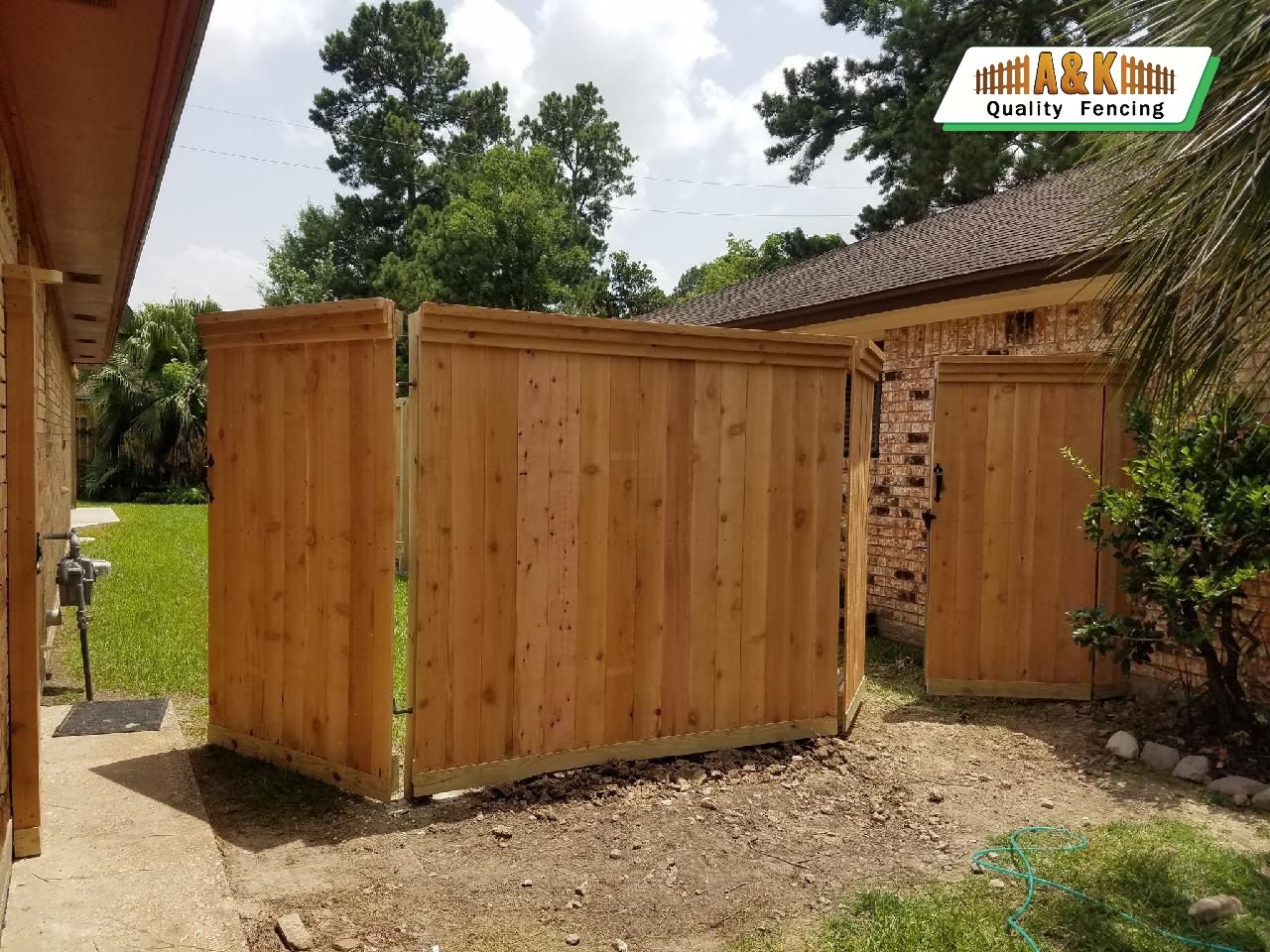 A wooden fence is in the backyard of a house.