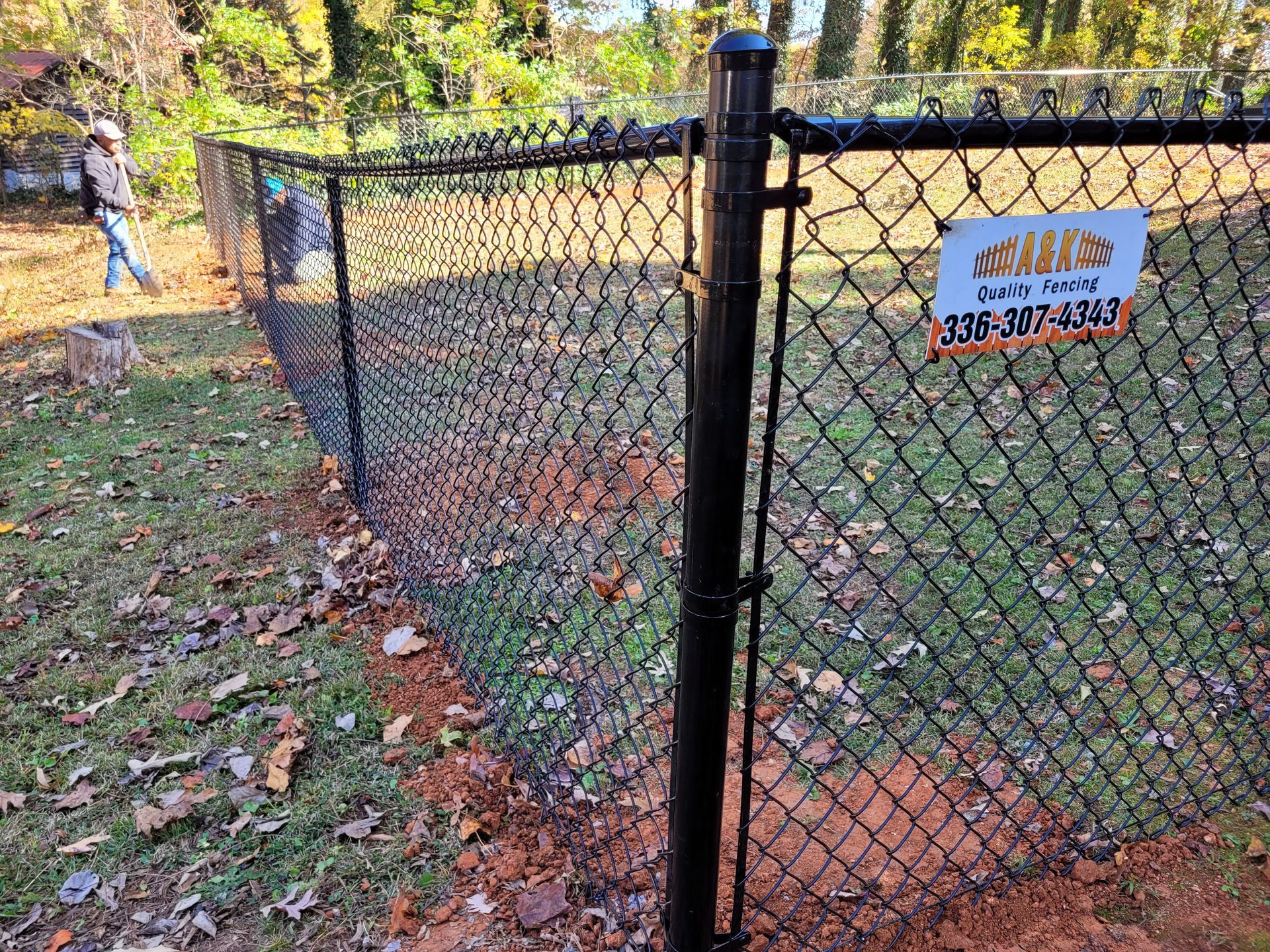 A chain Black  link fence is being installed in a yard.