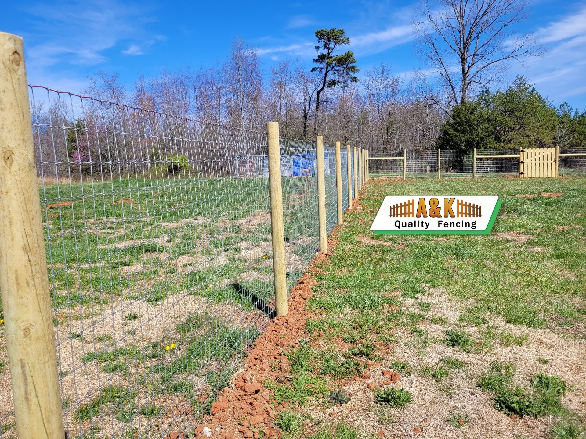 A wooden field fence is being built in a grassy field.
