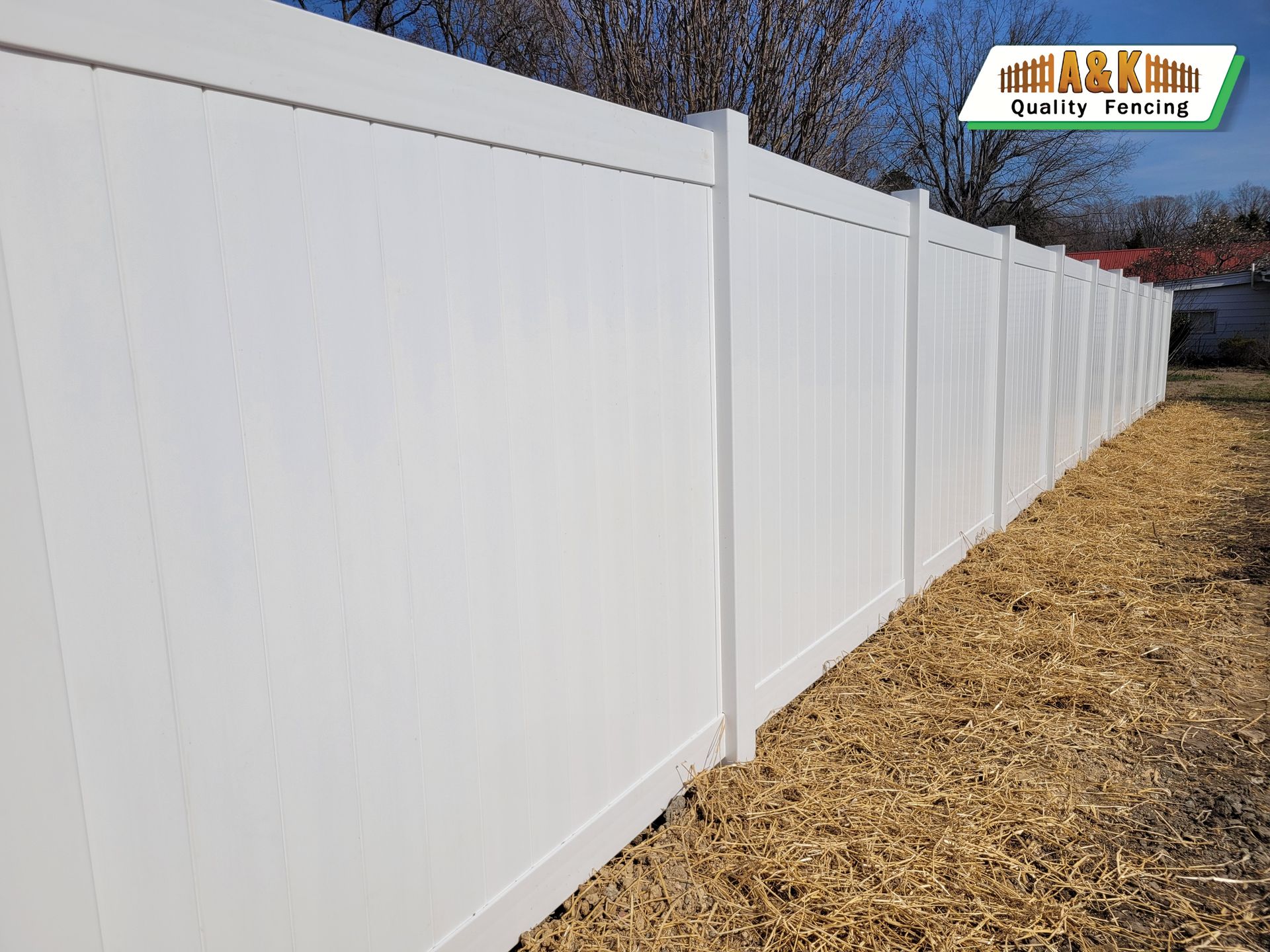 A white vinyl fence is sitting in the middle of a field.
