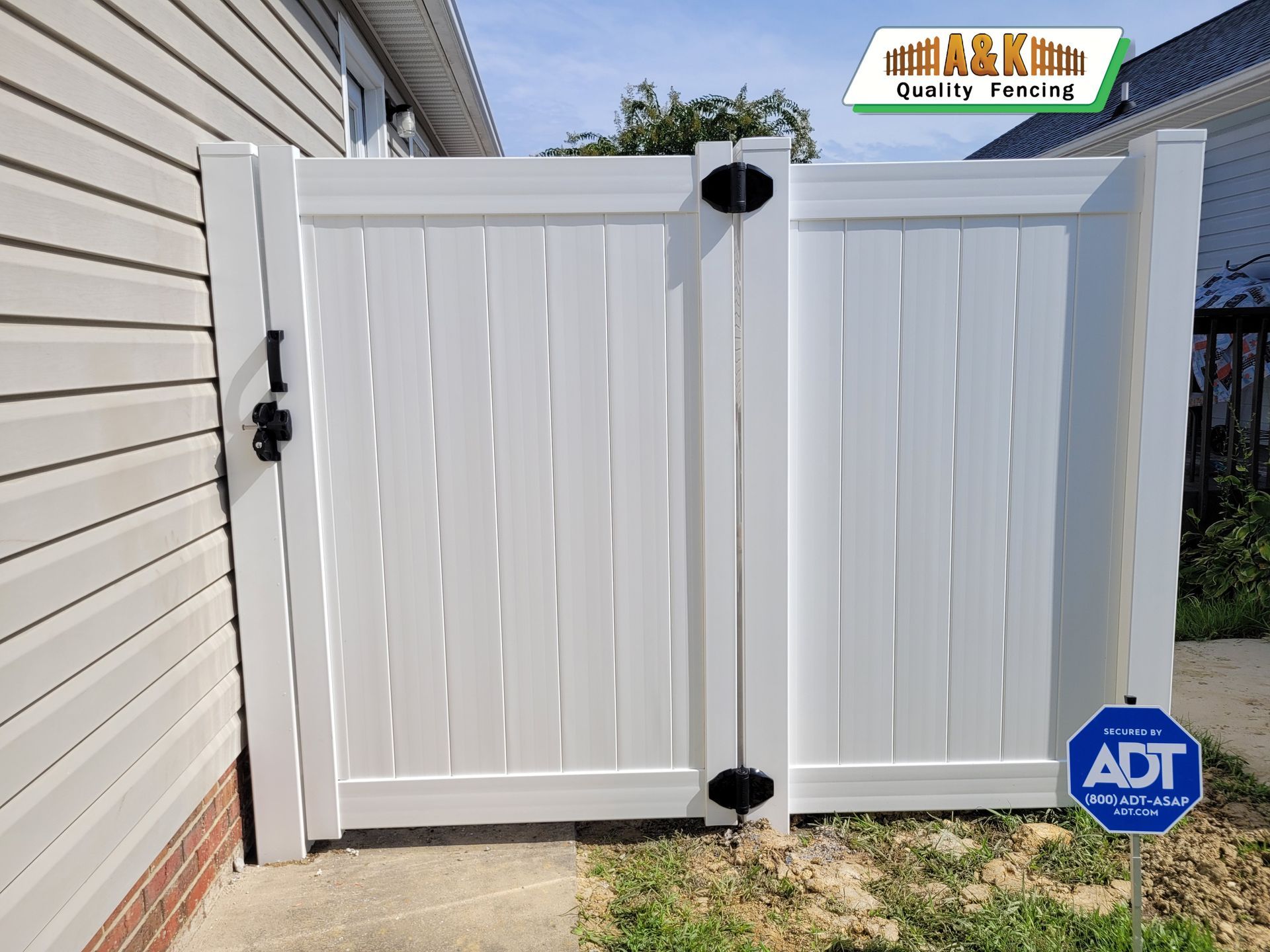 A white vinyl fence is sitting next to a house.