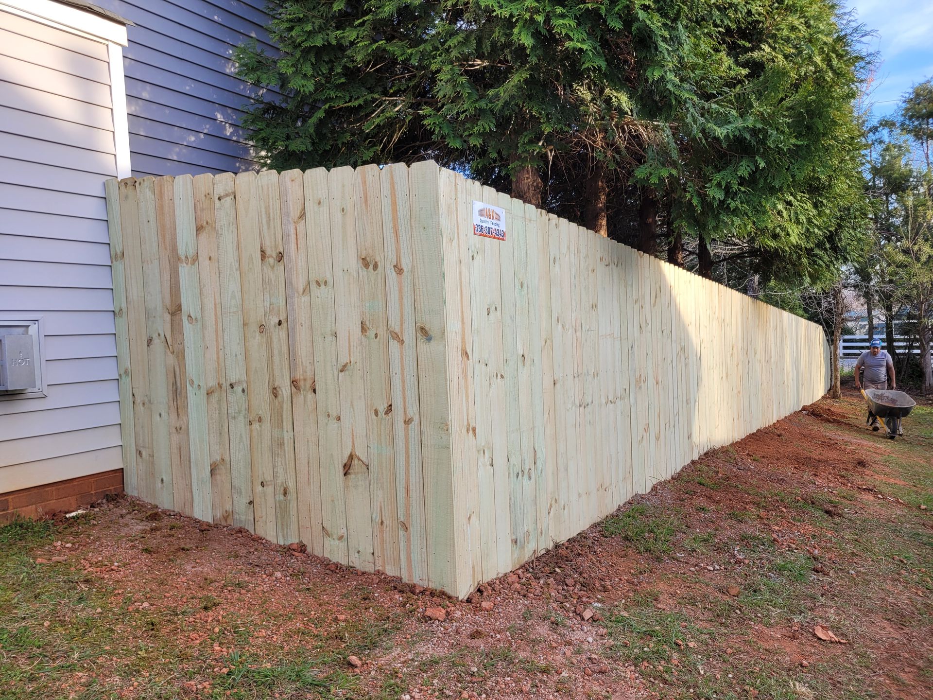 A wooden Privacy fence is being built in the backyard of a house.