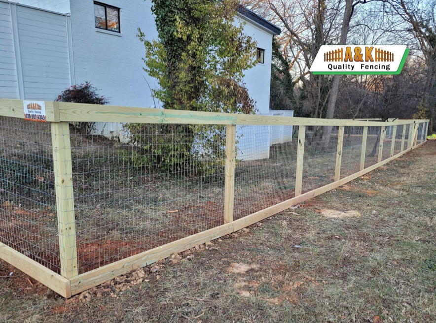 A wooden fence with a wire fence in front of a house.