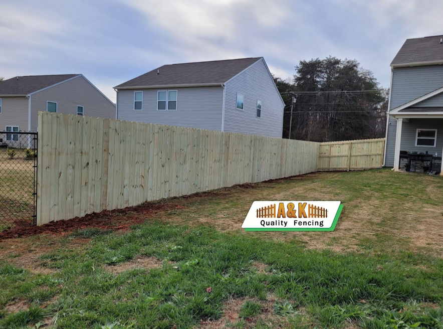 A wooden fence is in the backyard of a house.