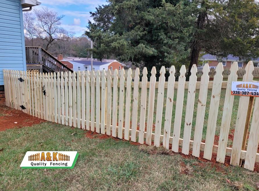 A wooden picket fence is in front of a house.