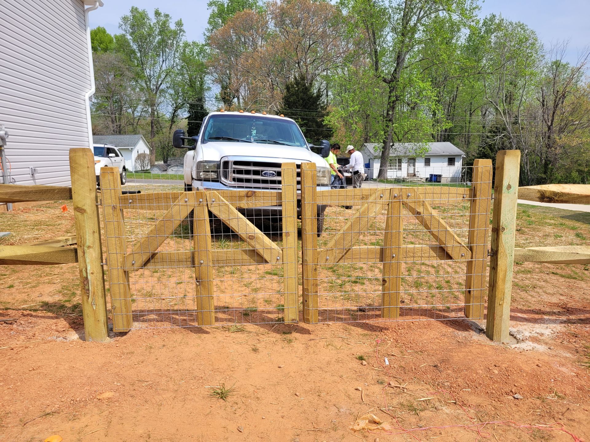 A wooden split rails with wire fence with a gate.