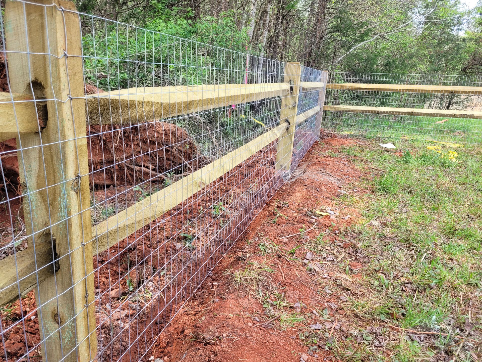 A wooden fence with a wire fence surrounding a field.