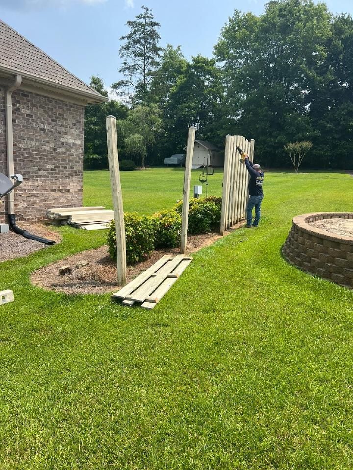 A man is standing next to a Vinyl fence in a yard.