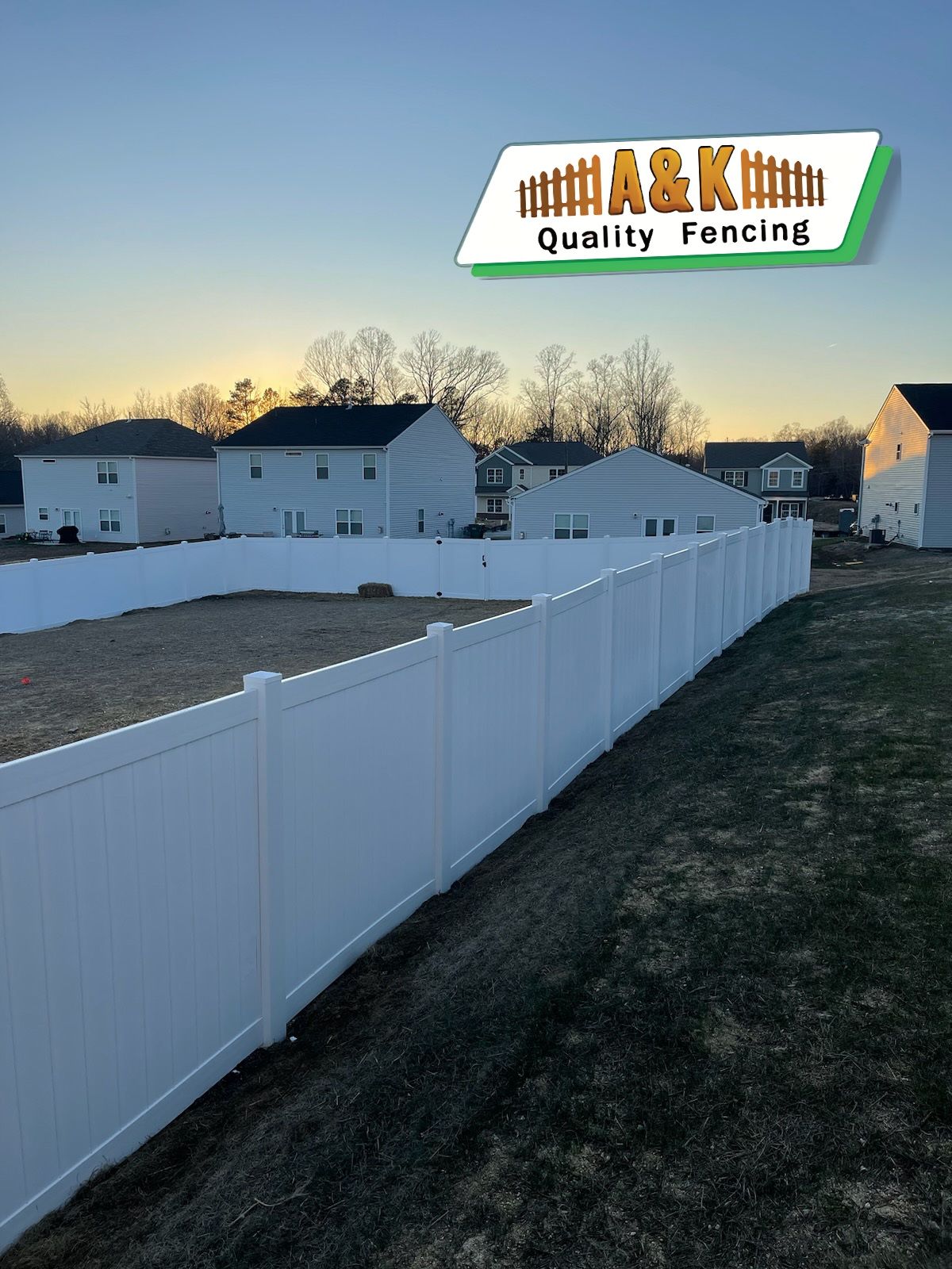 A white Vinyl fence surrounds a residential area with houses in the background.