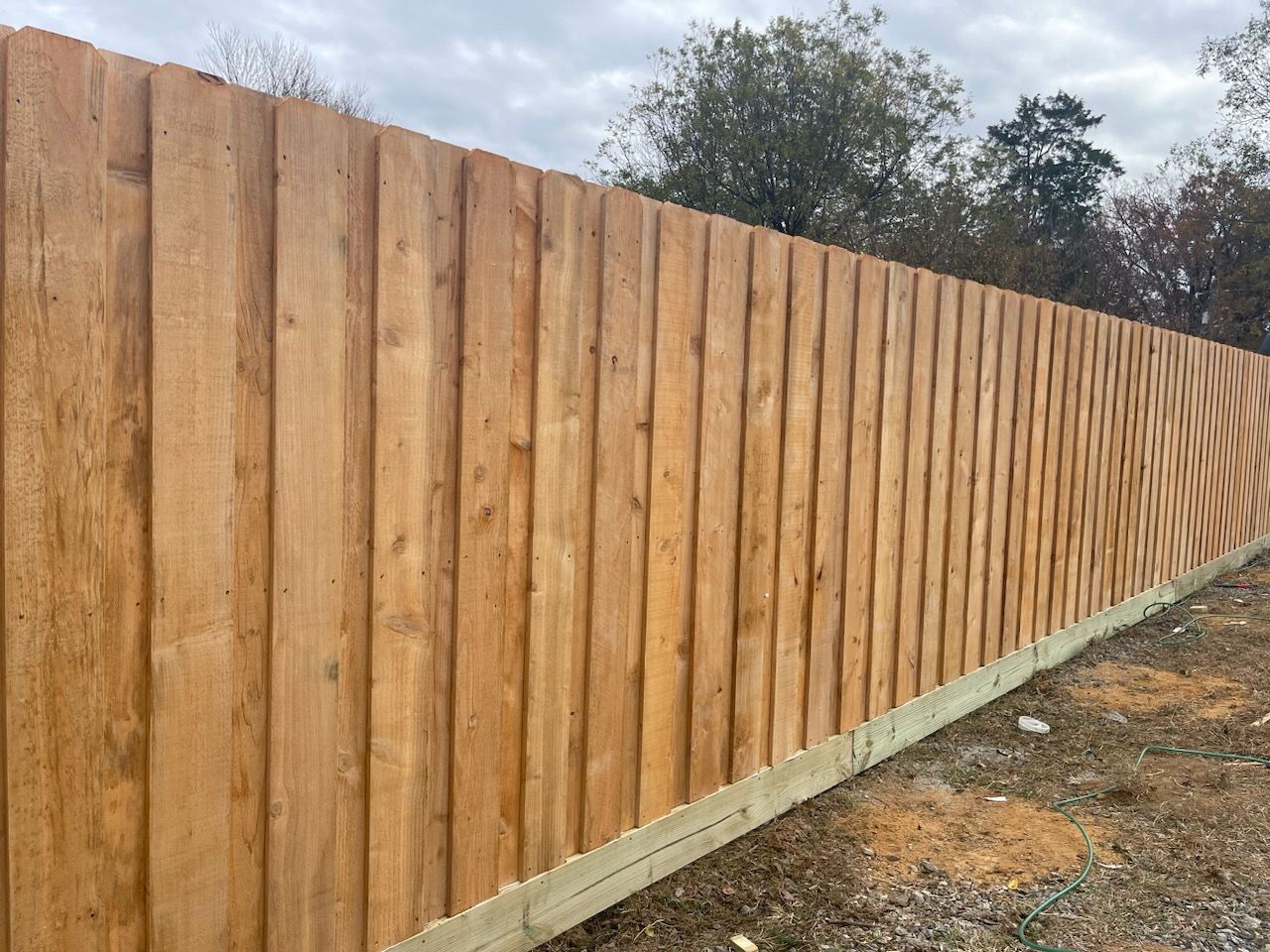 A wooden Privacy fence is sitting on top of a dirt field.