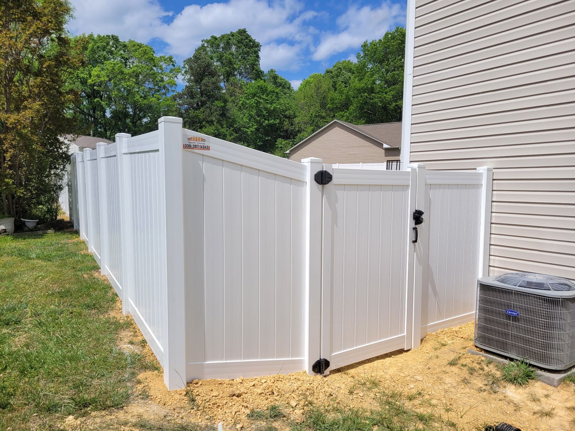 White picket fence with decorative lattice top, bordering a flower bed with colorful blooms.