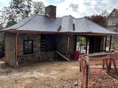 Stone building under construction with slate roof and copper gutters.