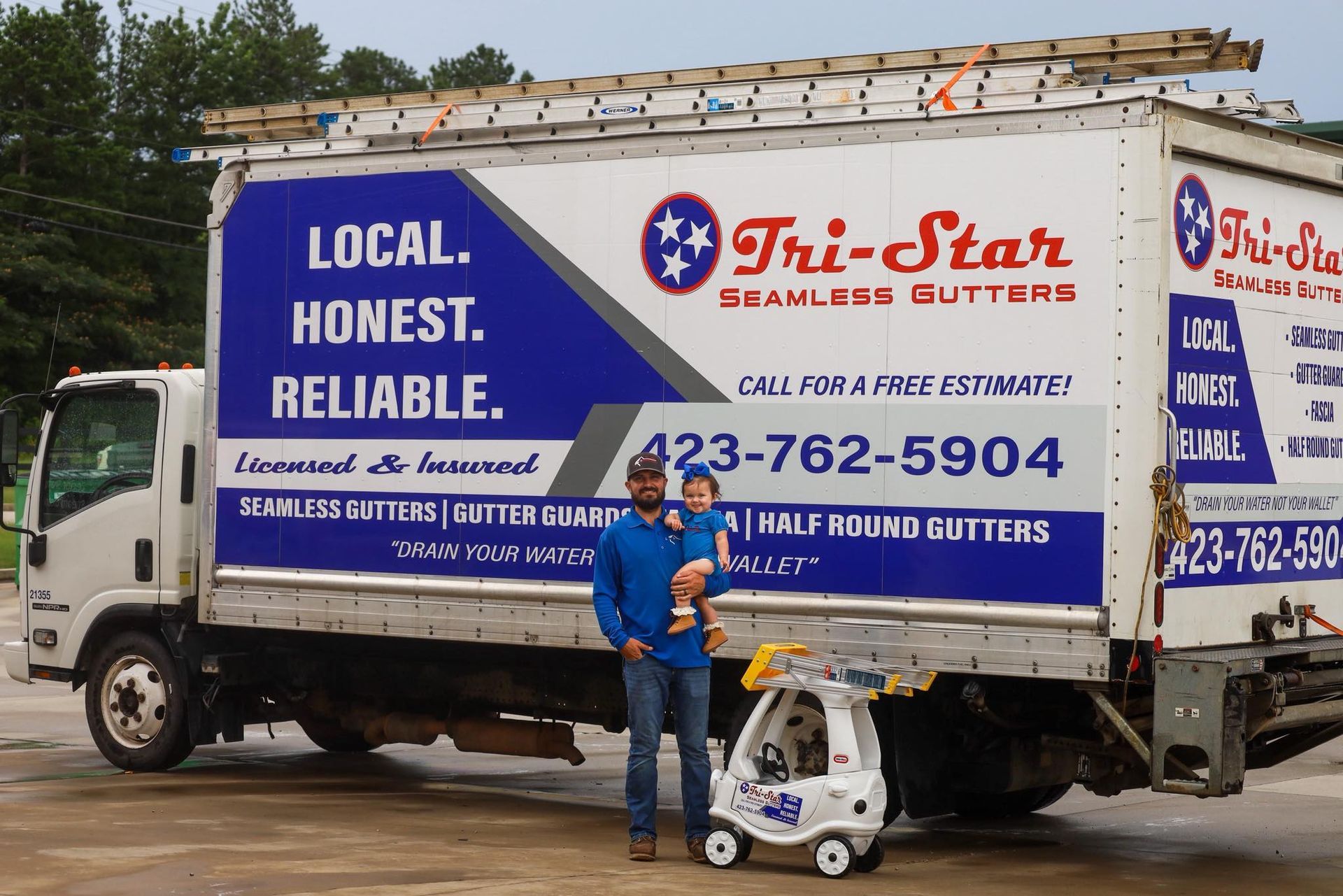 Man holding child stands next to a truck with 