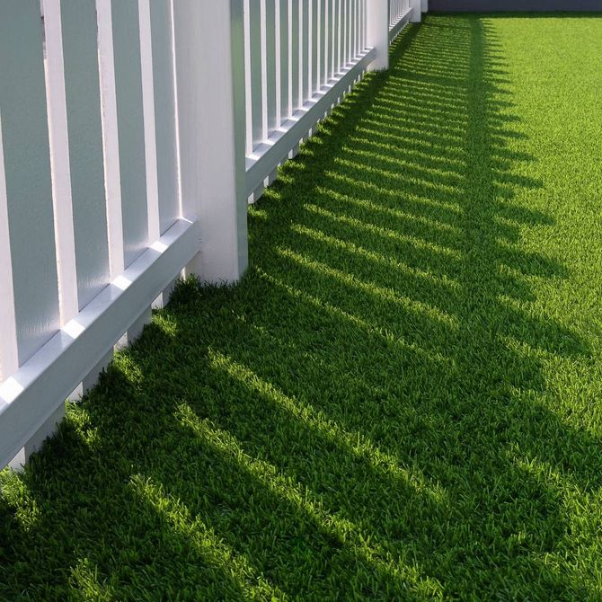 A white fence surrounds a lush green lawn
