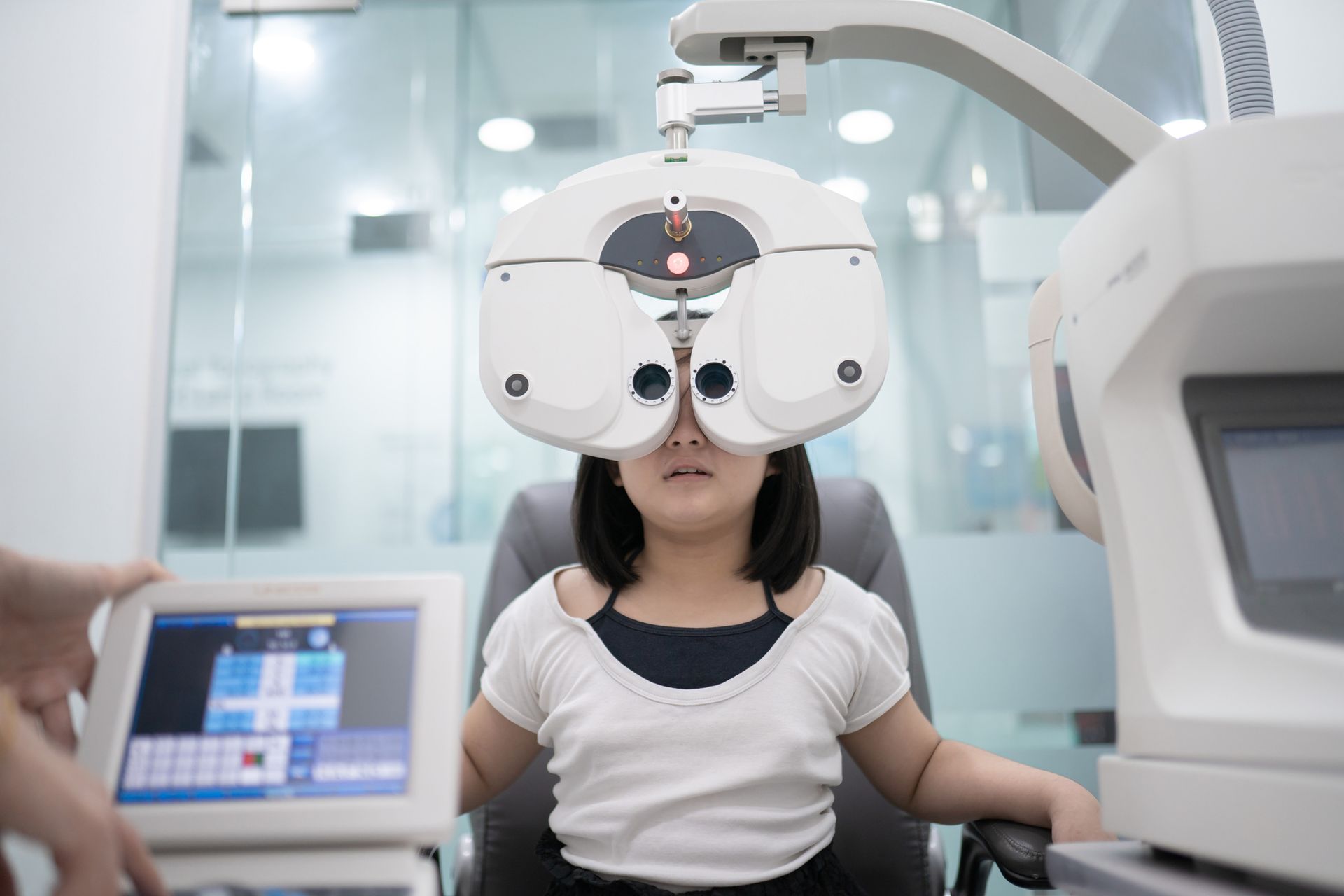 Young girl having an eye exam with a digital phoropter in an ophthalmology clinic 