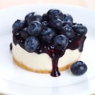 Blueberry cheesecake with fresh blueberries and syrup on a white plate