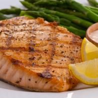 Grilled salmon fillet with asparagus and lemon wedges on a plate