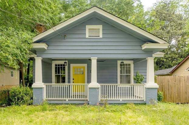 A dining room with a table and chairs and a wooden staircase.