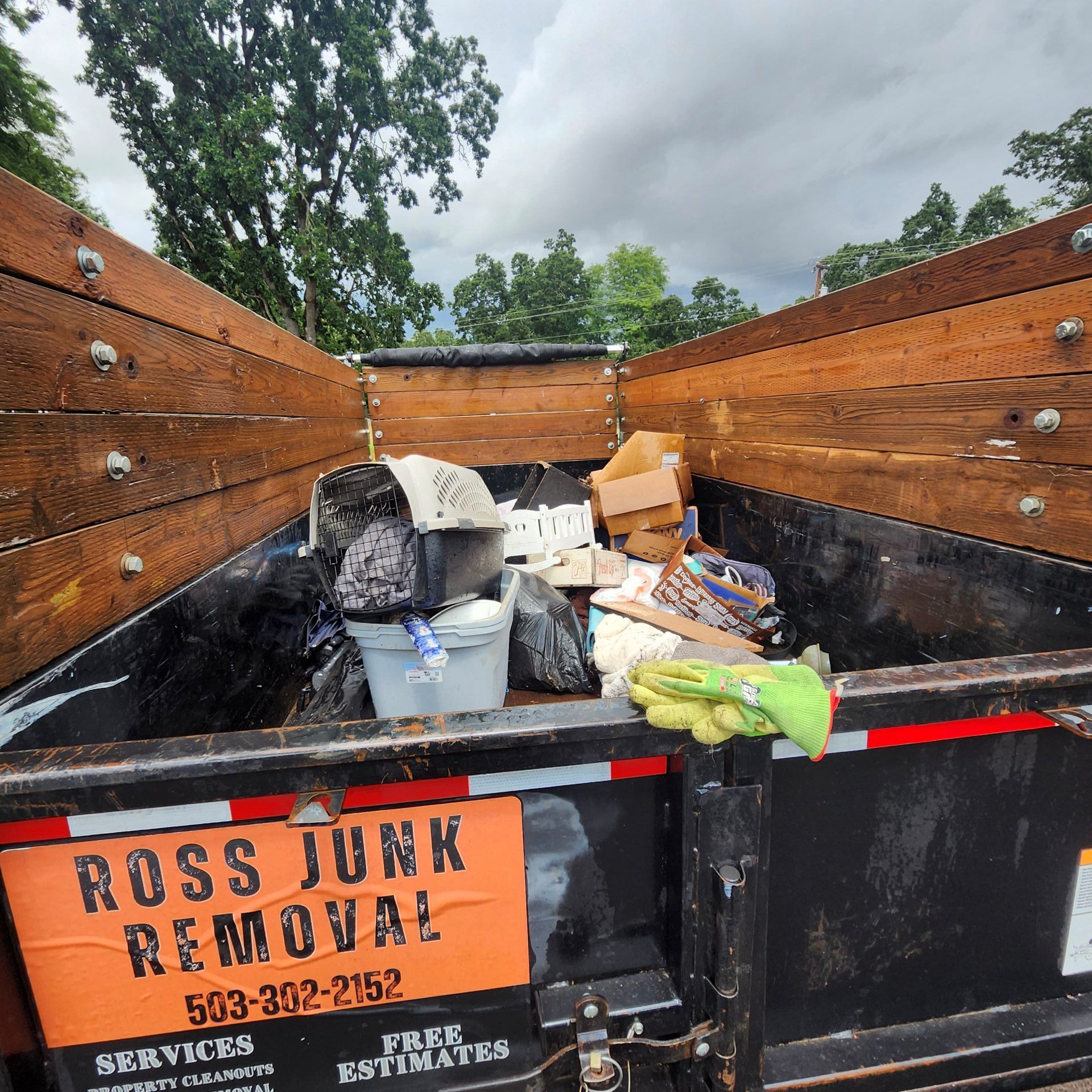 Dumpster with junk inside; Ross Junk Removal sign on the side.