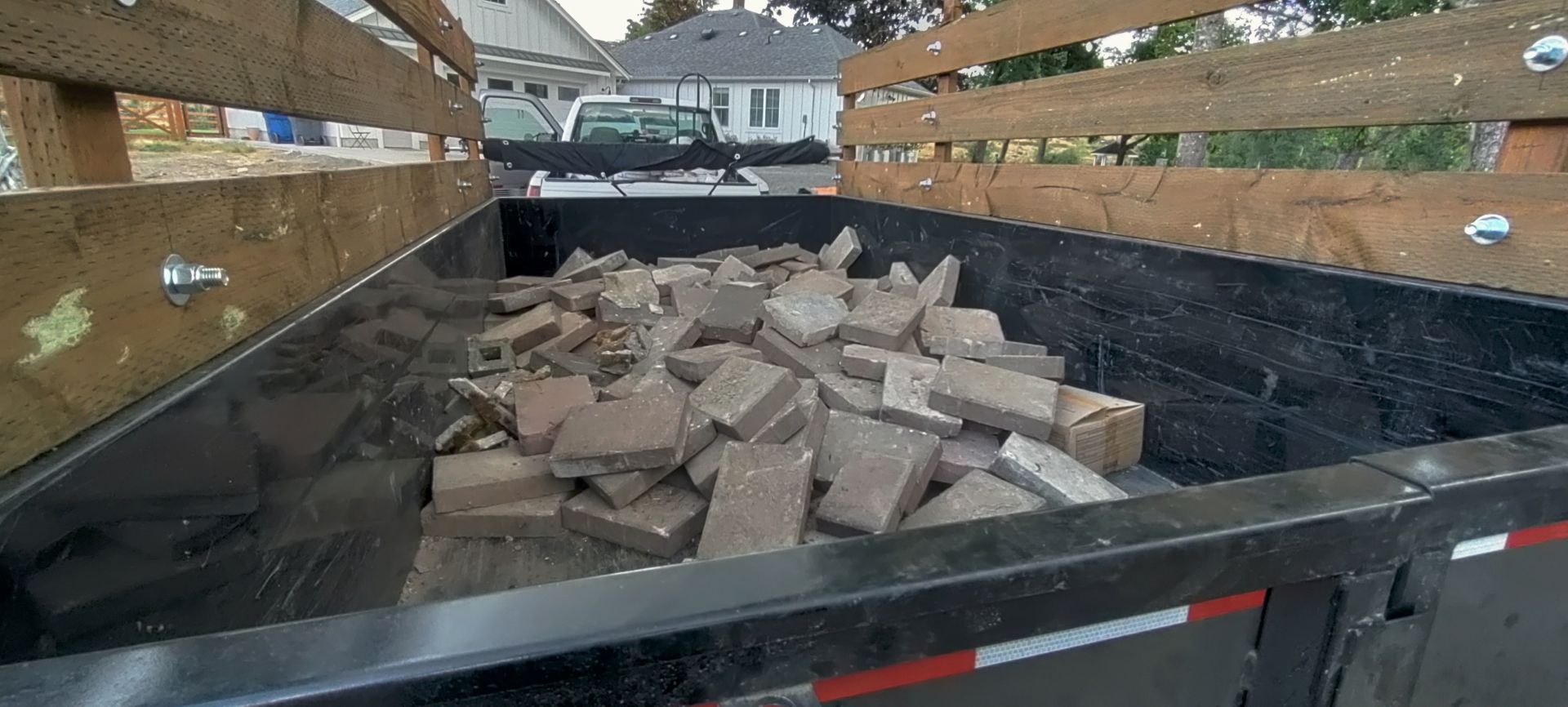 A black trailer bed filled with brown broken concrete pieces.