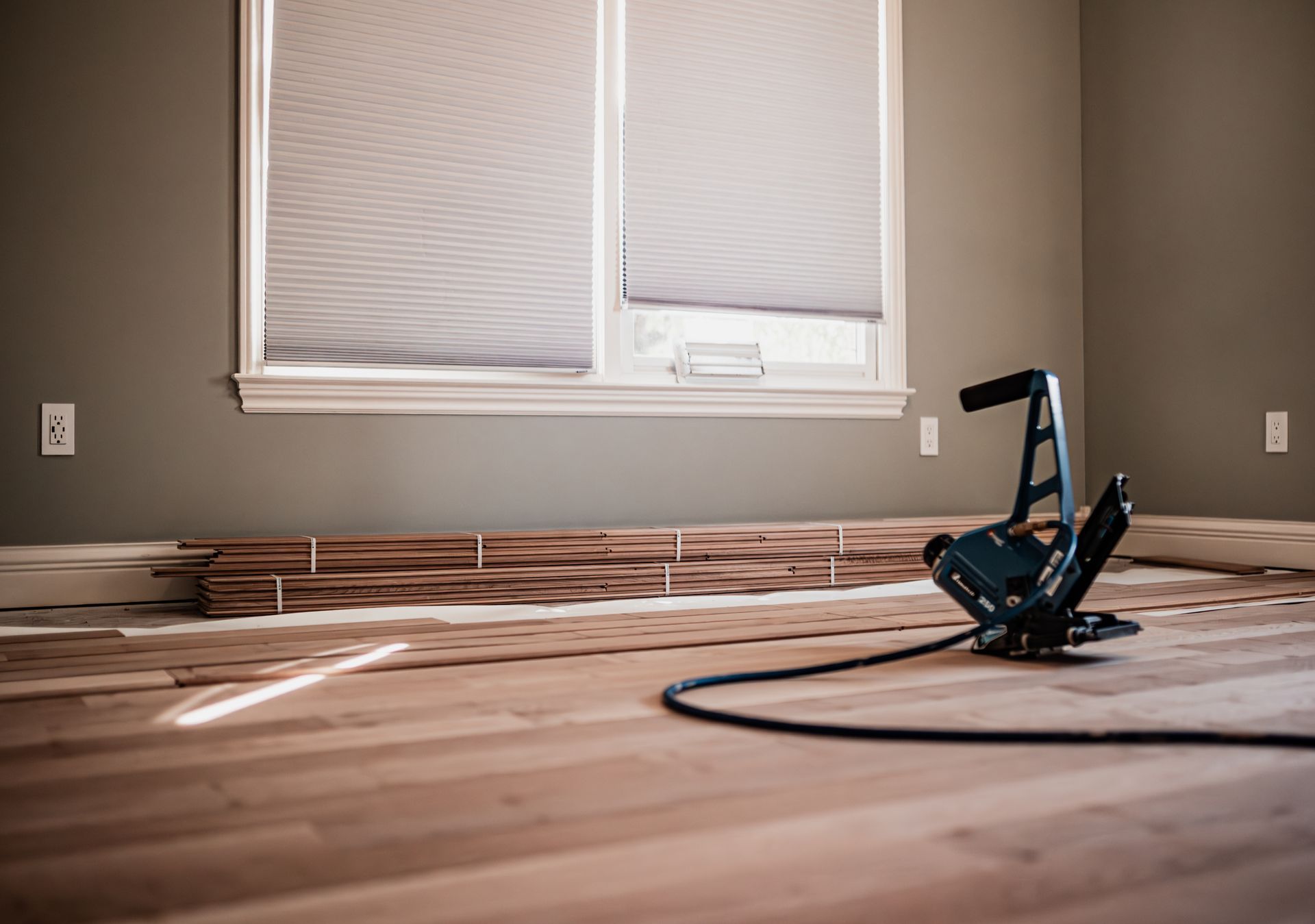 A wooden floor is being installed in a room with a window.
