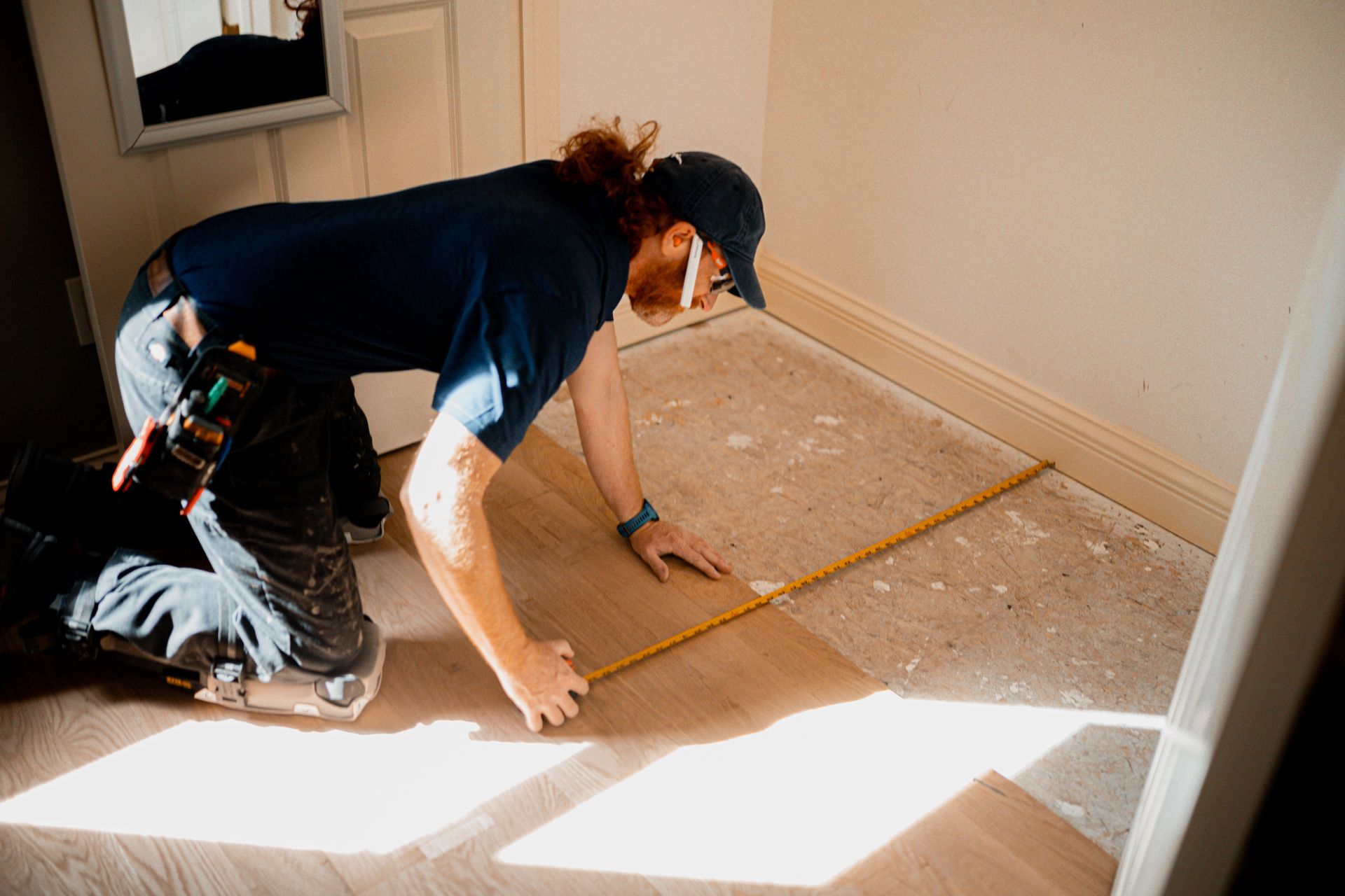 A man is measuring a wooden floor with a tape measure.