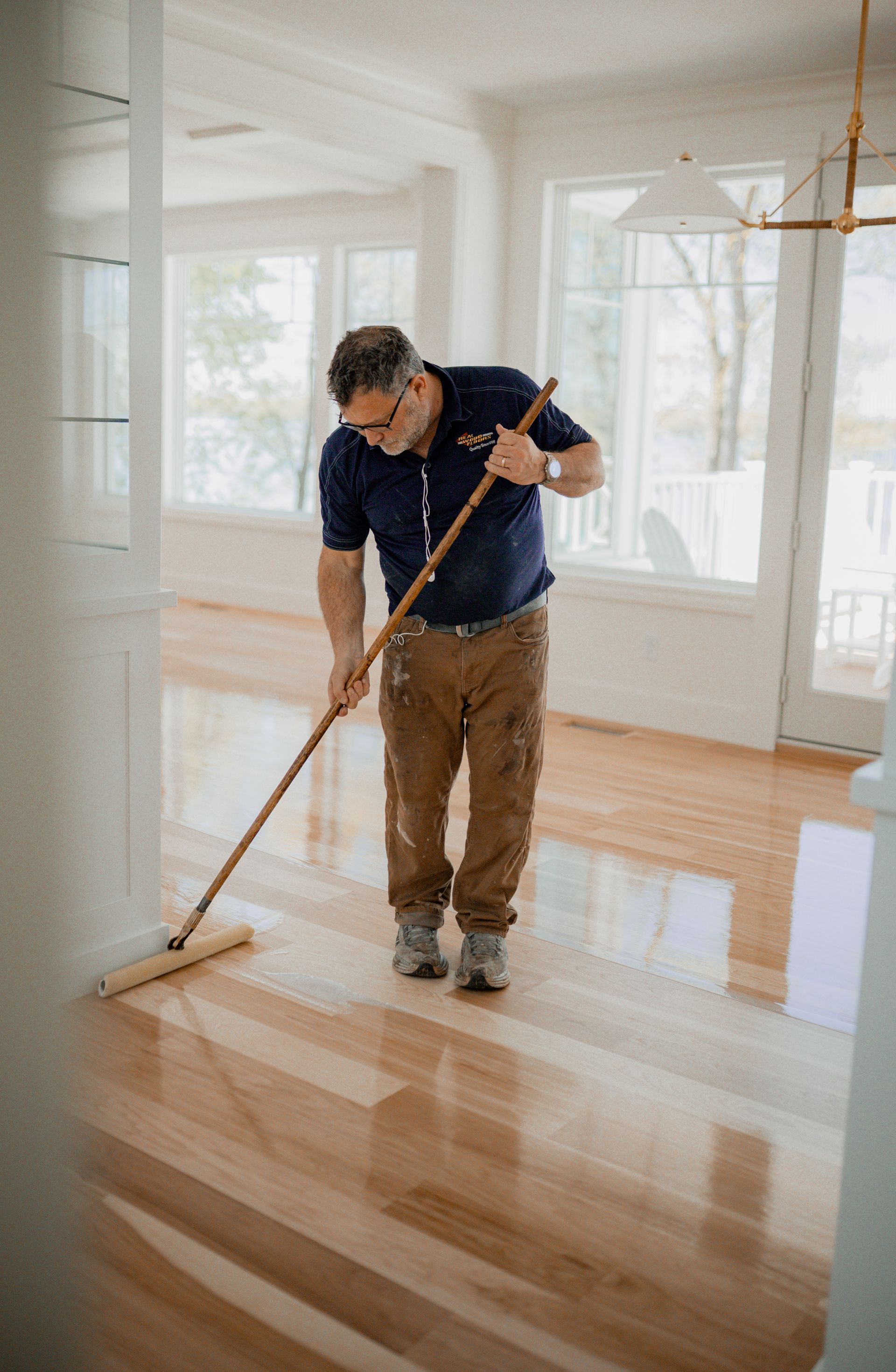A man is cleaning a wooden floor with a mop.