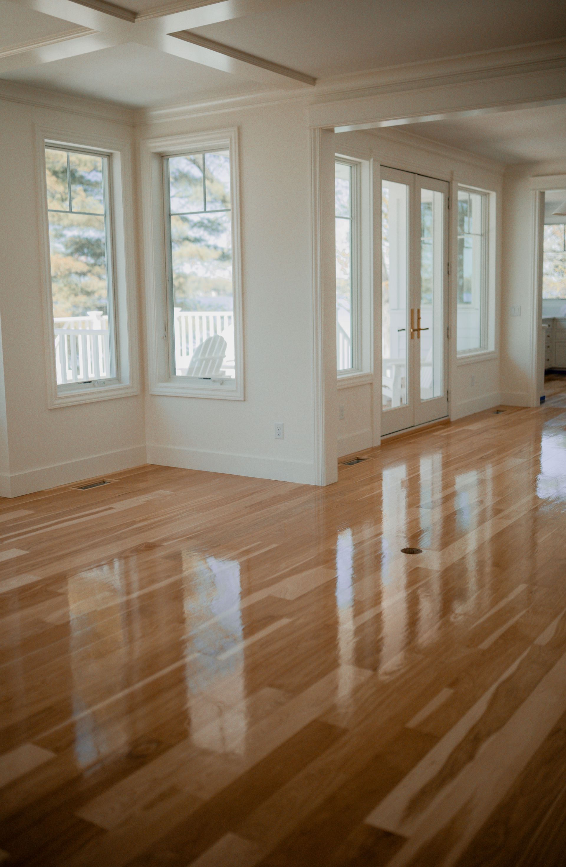An empty living room with hardwood floors and white walls.