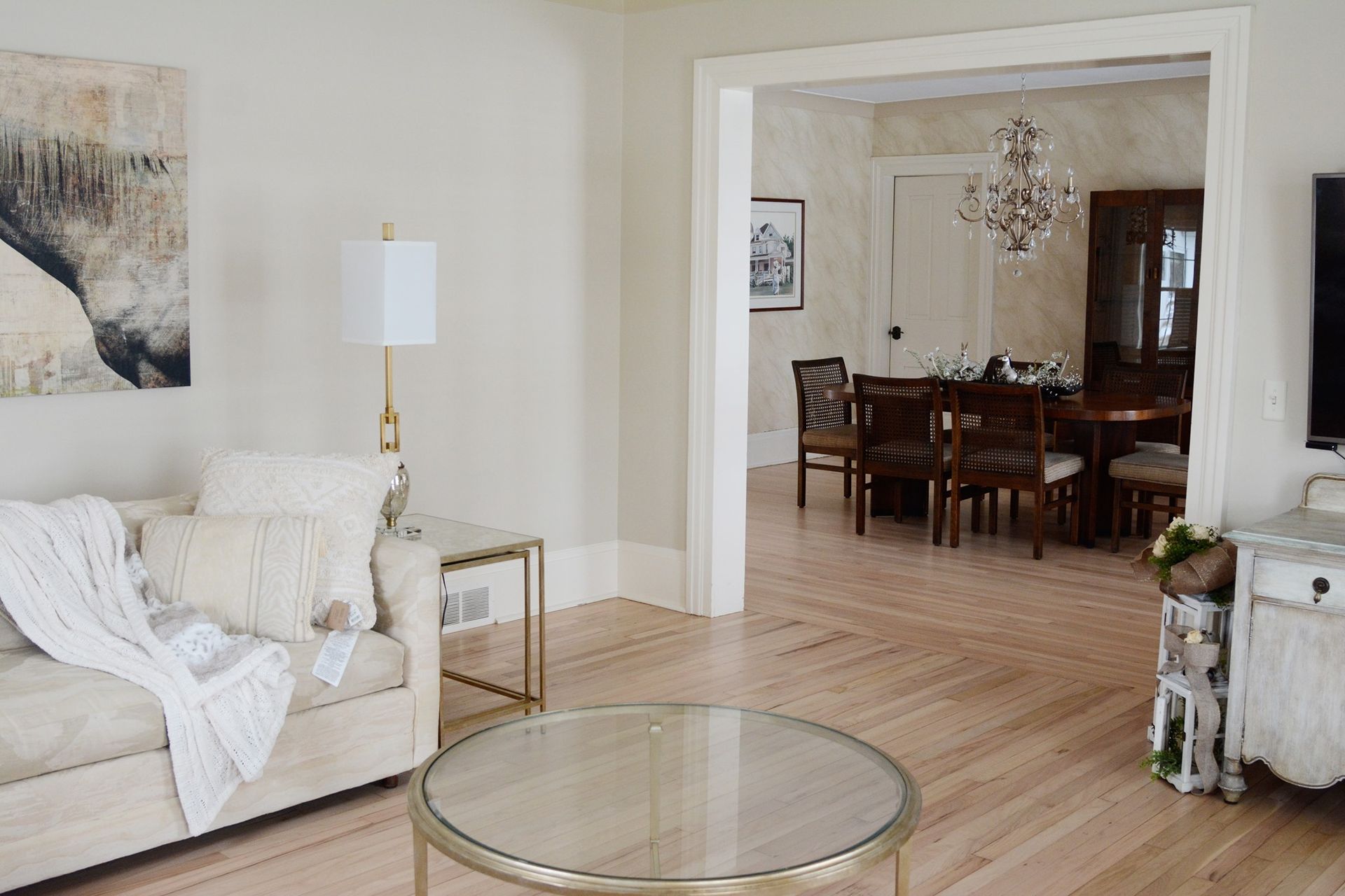A living room with a couch , coffee table , and dining room in the background.