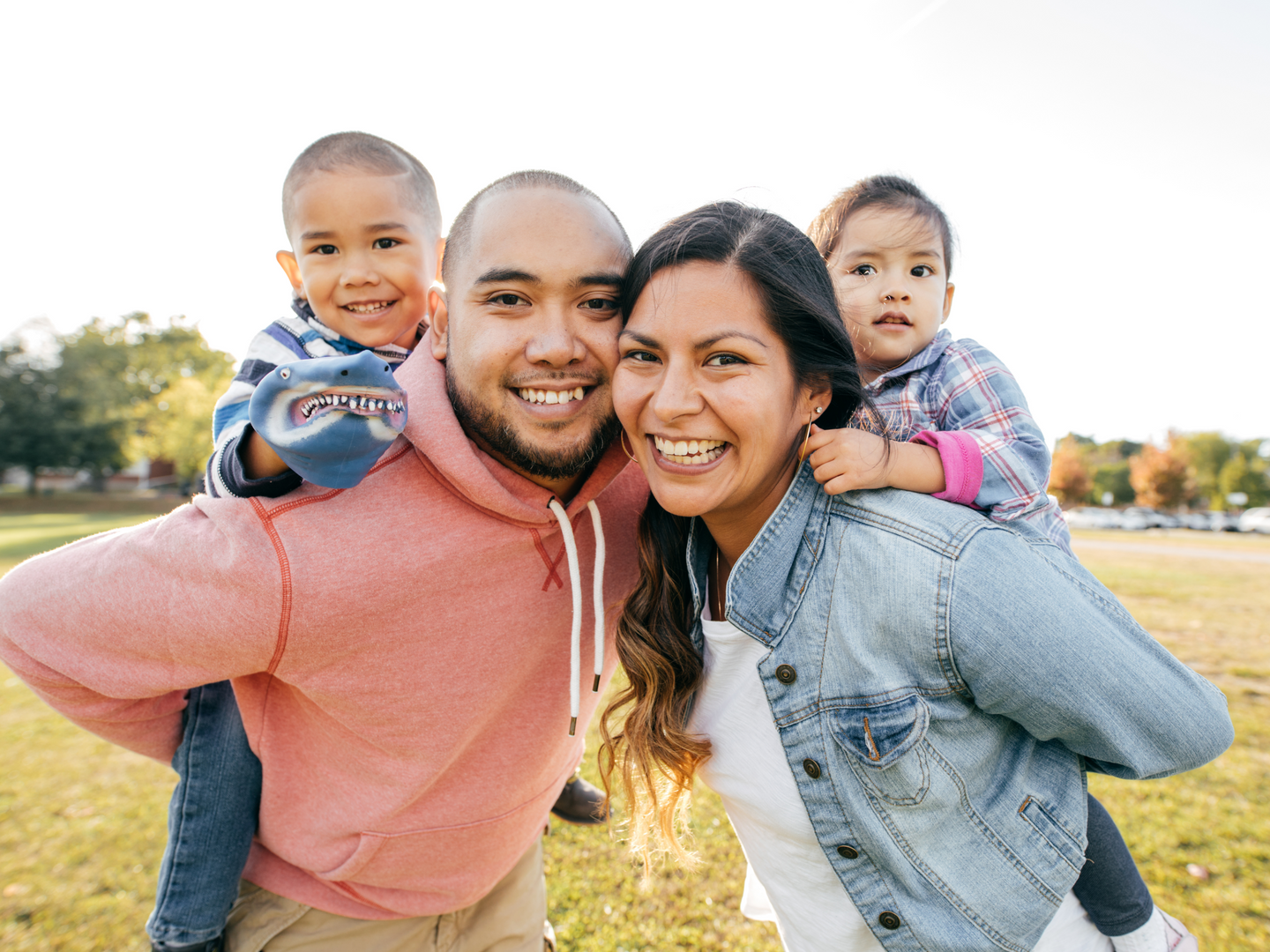 A smiling family with children riding on the parents backs