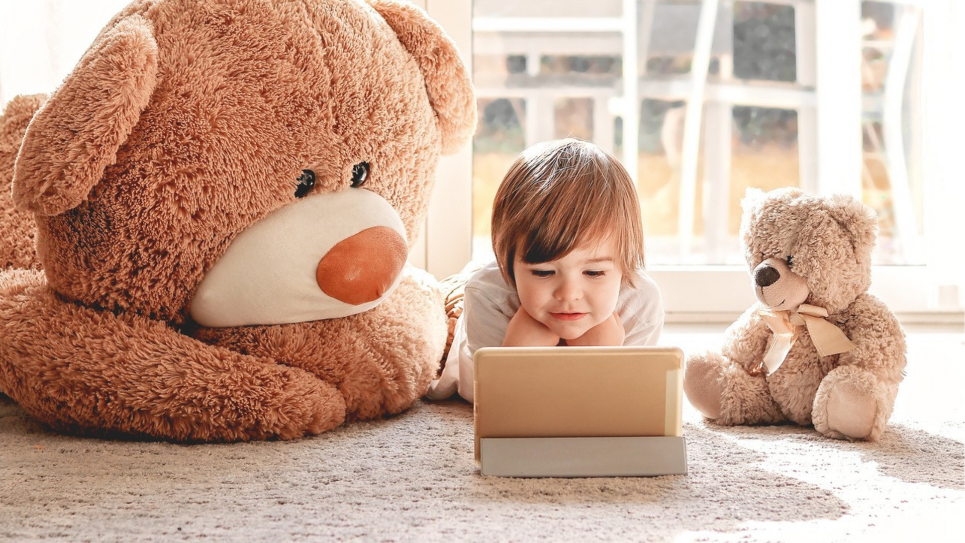 A little boy viewing a tablet with toy bears