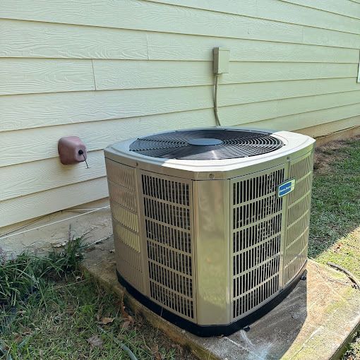 An air conditioner is sitting on the side of a house.