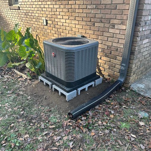 An air conditioner is sitting on the side of a brick building.