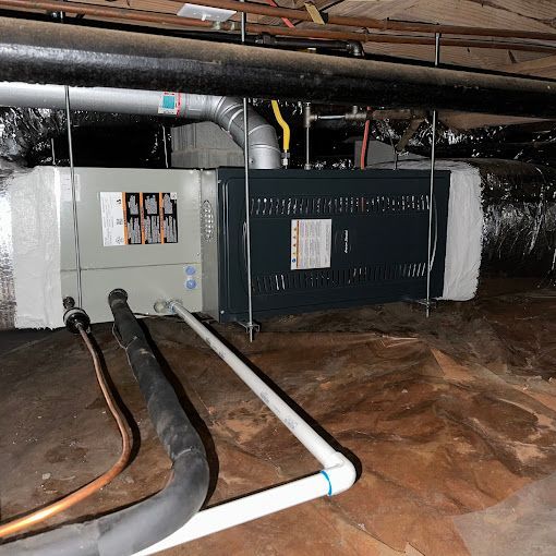 An air conditioner is hanging from the ceiling in a basement