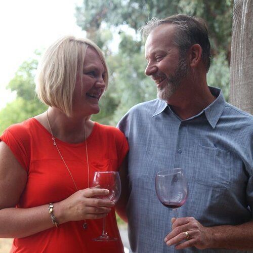 A man and a woman are standing next to each other holding wine glasses.