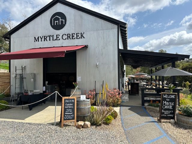 A large white building with a red awning is called myrtle creek.