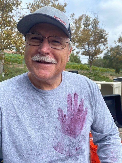 A man wearing glasses and a hat has a hand print on his shirt