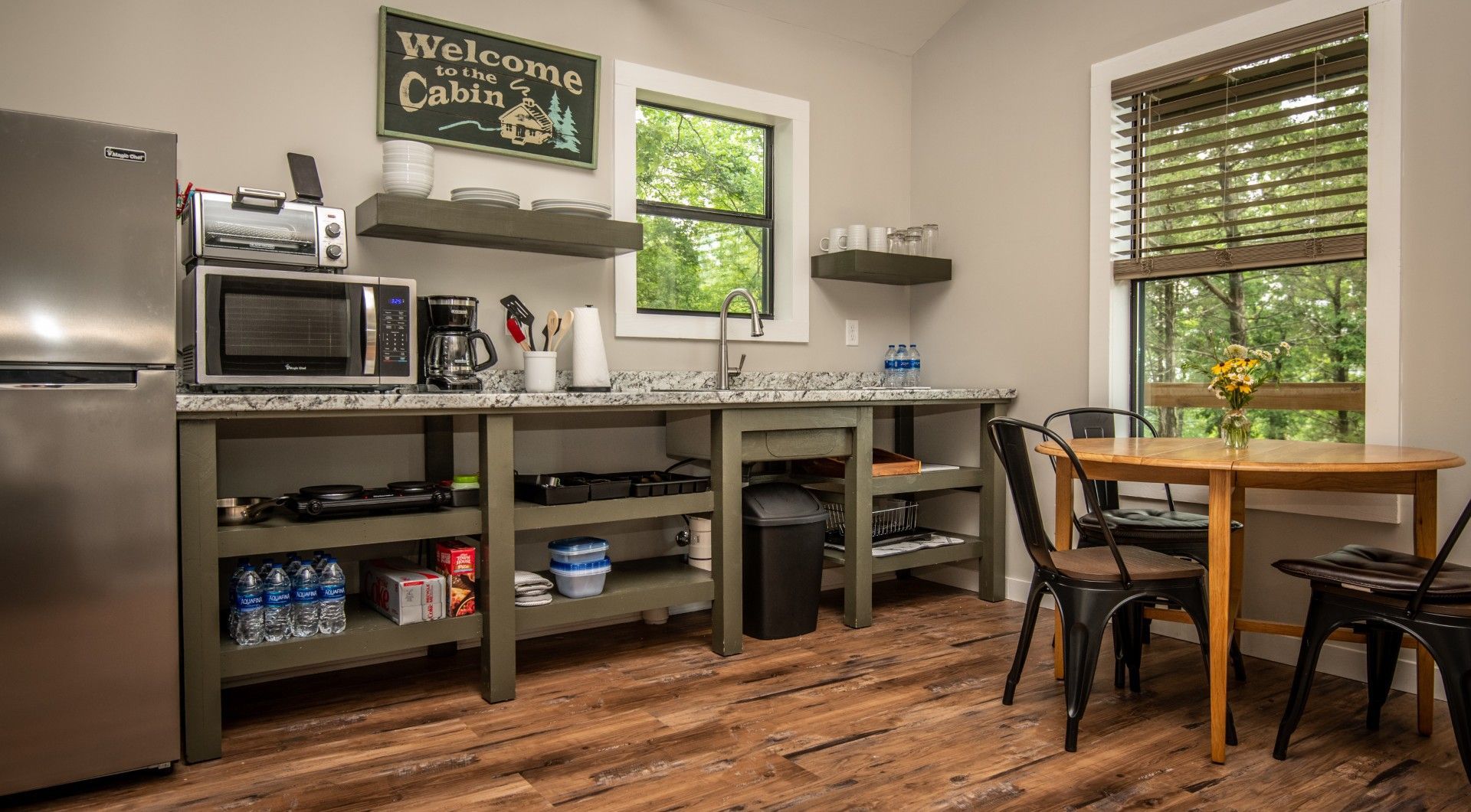 Small cabin kitchen with stainless steel fridge, microwave, and small dining table.