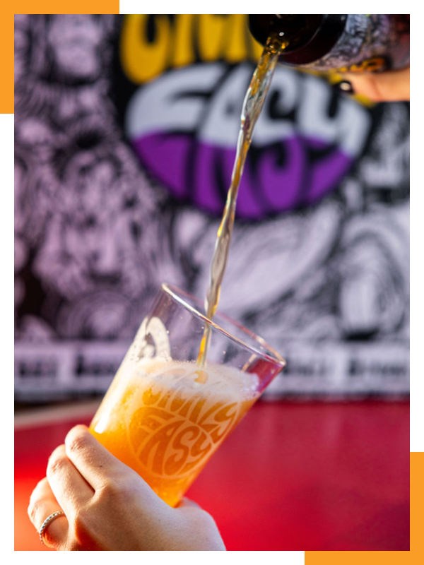 a person is pouring beer into a glass with a purple and yellow background .